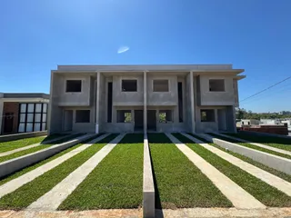 Fachada frontal de uma casa moderna com paisagismo e calçadas.