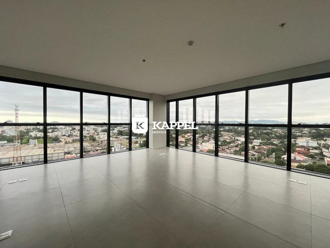 Vista panorâmica da cidade vista através de grandes janelas de uma sala ampla.