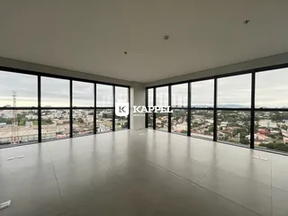 Vista panorâmica da cidade vista através de grandes janelas de uma sala ampla.