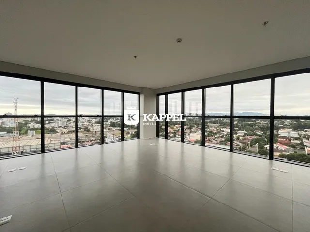Vista panorâmica da cidade vista através de grandes janelas de uma sala ampla.