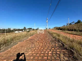 Uma estrada de tijolos vermelhos atravessa uma área gramada ao lado de postes de energia.