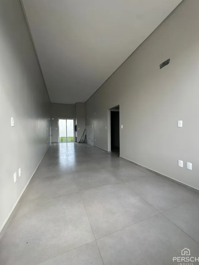 Corredor longo e vazio com piso de cerâmica e paredes claras.