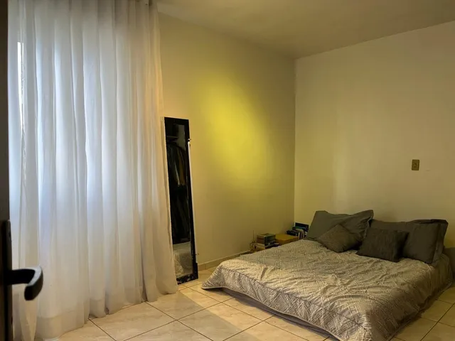 Foto de um quarto com cama e cortinas brancas.