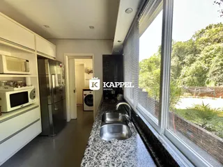 Cozinha moderna com bancada e vista para a vegetação.