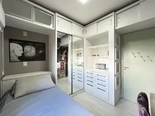 Quarto com armários brancos e cama em um imóvel no Brasil.