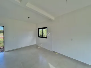 Ambiente interno de uma sala ampla com paredes brancas e piso claro.