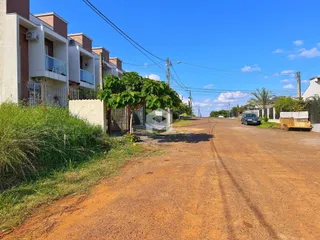 A foto mostra a fachada de um conjunto de casas em uma rua de terra.