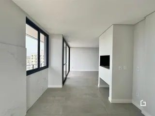 Ambiente interno de uma sala ampla com grandes janelas e piso claro.