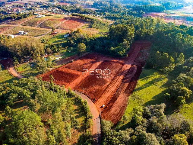 Vista aérea de uma propriedade rural com áreas de terra arada e vegetação circundante.