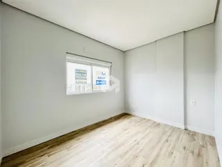A sala apresenta paredes brancas e piso de madeira clara.