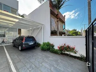 Vista da fachada de uma residência com área pavimentada e vegetação em Lajeado, Brasil.