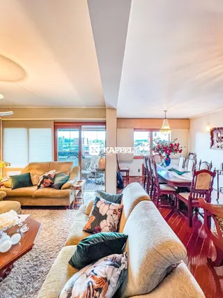 Sala de estar e jantar com sofás e mesa de madeira, oferecendo uma vista da cidade.