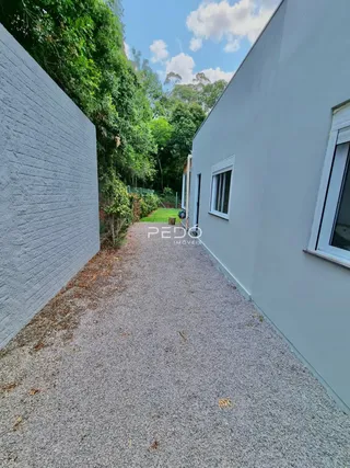 Parede lateral de uma residência em Lajeado, Brasil, com vegetação ao fundo.