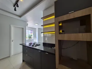 Vista da cozinha moderna com armários escuros e bancadas escuras.
