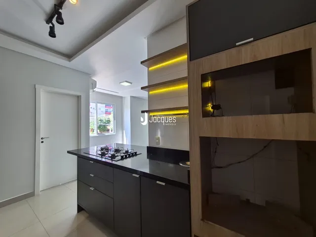 Vista da cozinha moderna com armários escuros e bancadas escuras.