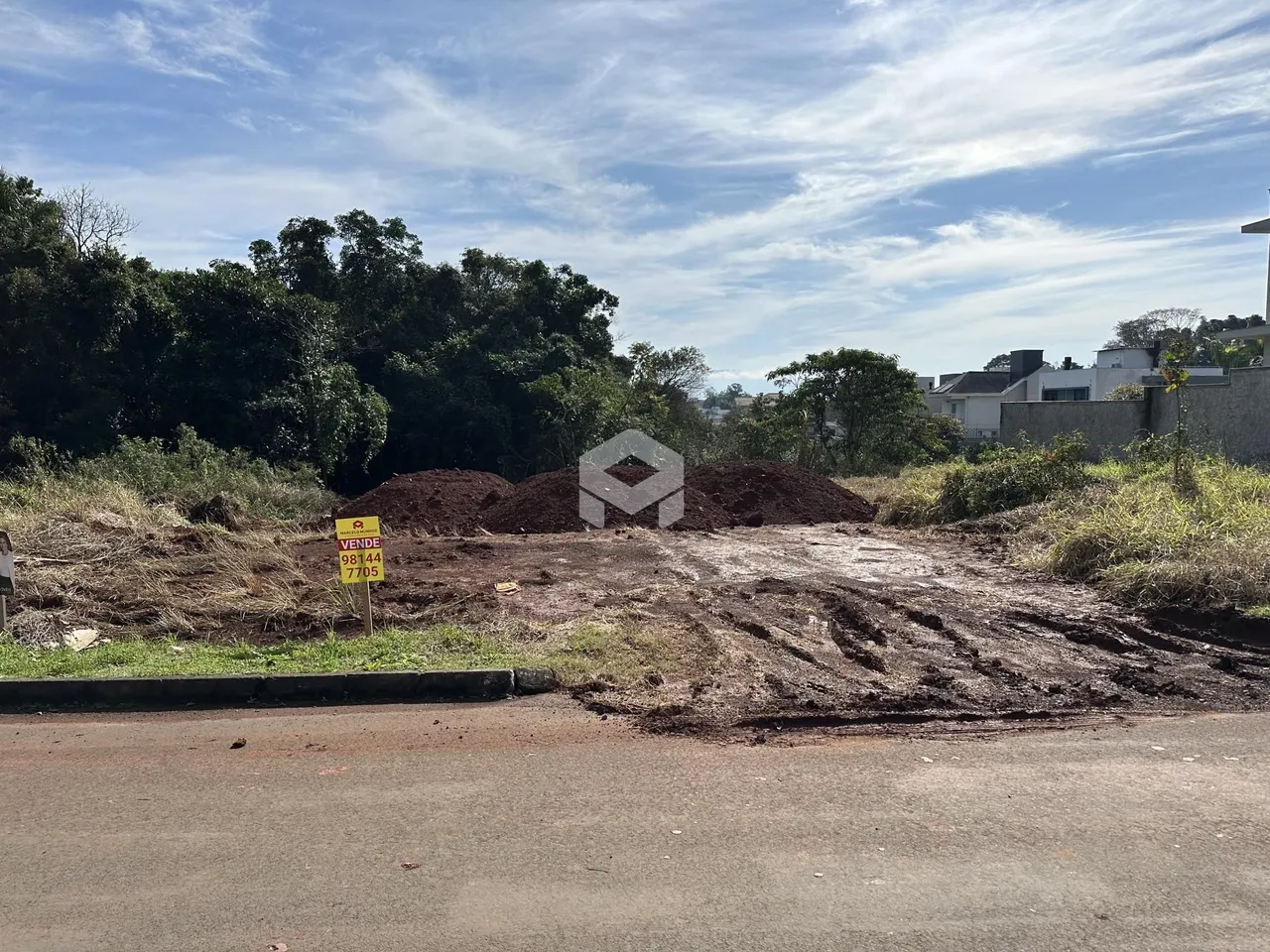 Vista externa de um terreno com terra exposta e vegetação densa.
