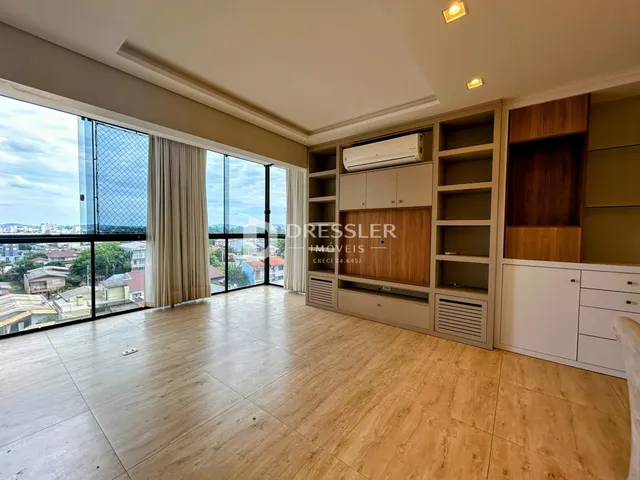 A sala de estar possui piso de madeira e grandes janelas com vista para a paisagem.