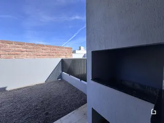 Vista externa de um pátio com muro e cerca de metal.