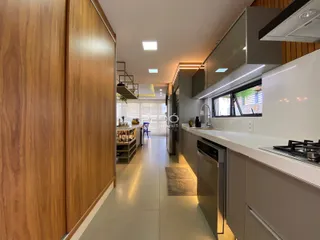 Vista interna de uma cozinha moderna com armários de madeira e bancadas brancas.