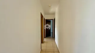 Corredor interno de uma residência com paredes brancas e piso de cerâmica.
