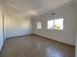 Foto de um cômodo amplo com piso de madeira e janela.