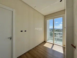 Interior de uma sala com piso de madeira e porta branca.