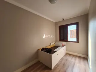 Vista interna de um corredor com parede neutra e janela de madeira.