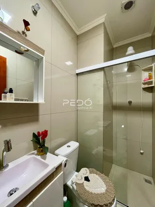 Foto interna de um banheiro com revestimento cerâmico e box de vidro.