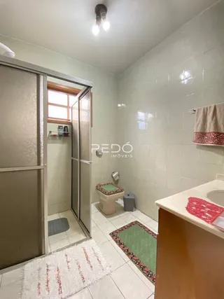 Um banheiro com revestimento cerâmico branco e vaso sanitário visível.
