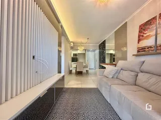 Sala de estar com sofá branco e painel decorativo branco na parede.
