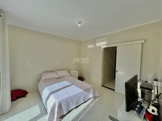 Quarto com cama e armário branco em ambiente claro.