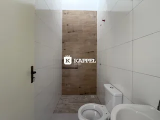 Este é um banheiro com paredes brancas e um painel de madeira no interior.