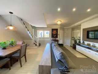 Foto de uma sala de estar com piso de madeira e escadaria visível.