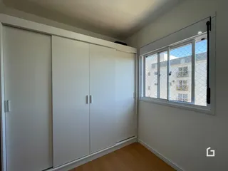 Ambiente interno com armários brancos e janela de grande porte.