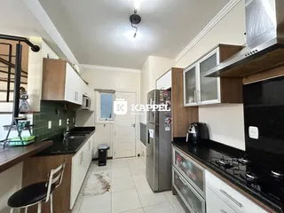 Cozinha com armários de madeira e bancadas escuras em um imóvel em Lajeado.