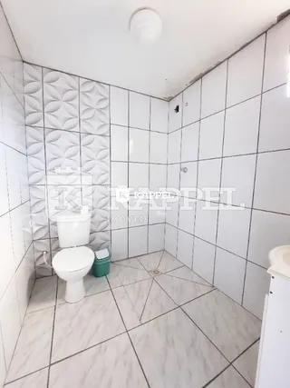 Banheiro com paredes e piso revestidos em azulejos brancos.
