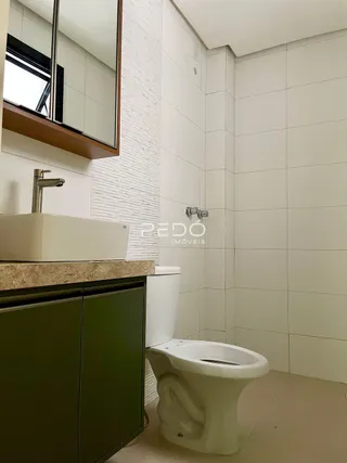 Foto de um banheiro com pia e vaso sanitário em cerâmica branca.