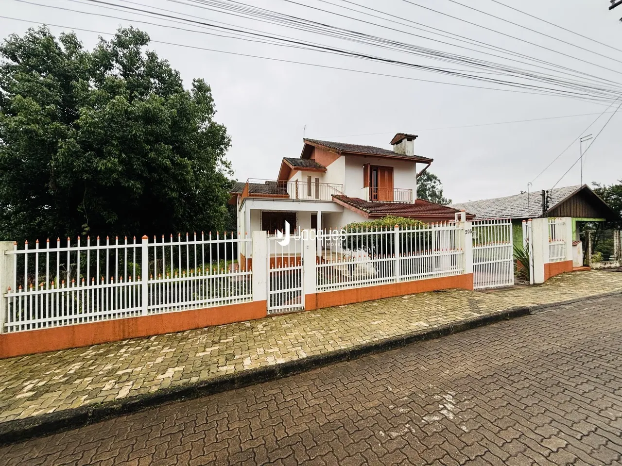Fachada de uma residência em Lajeado, Brasil com cerca e portão brancos.