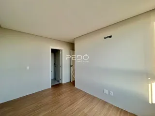Interior de um ambiente com piso de madeira clara e paredes brancas.