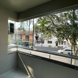 Vista da varanda mostrando árvores e edifícios na área externa.