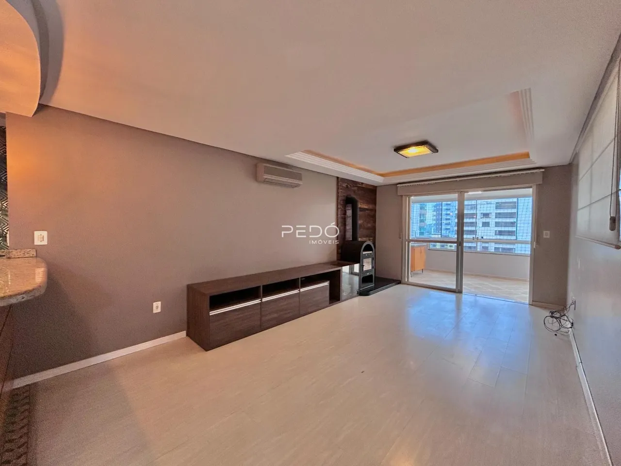 Ambiente interno de uma sala de estar com vista para a cidade.
