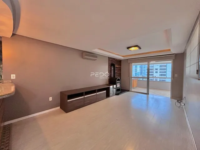 Ambiente interno de uma sala de estar com vista para a cidade.