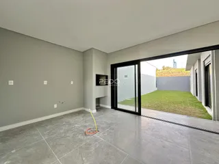 Ambiente interno moderno com piso de concreto e porta de vidro abrindo para o jardim.