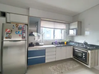 A cozinha apresenta armários brancos e eletrodomésticos de aço inoxidável.