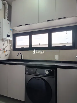 Foto de uma cozinha com armários brancos e bancada escura.