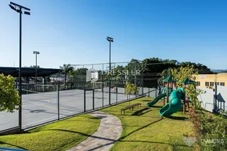 Vista externa de uma quadra esportiva cercada por cerca e gramado.