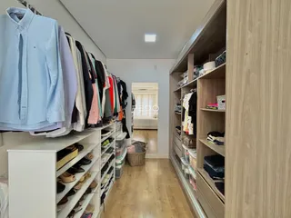 Um corredor interno com armários e roupas penduradas em um imóvel.