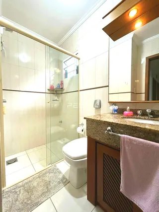 Banheiro com box de vidro e revestimento branco em imóvel no Brasil