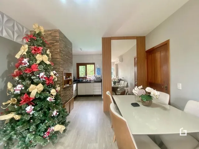 Interior de uma sala com árvore de Natal decorada contra uma parede de tijolos.