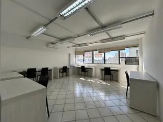 Ambiente interno de um escritório com piso de cerâmica e grandes janelas.